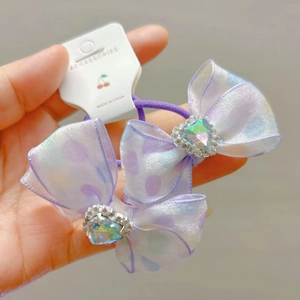 Detail van lila haarelastiekje met organza strik, stippen en hartvormige strass