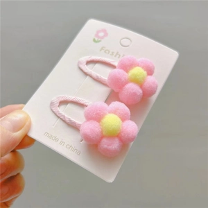 Close-up of pink and yellow plush flower hair clips on a white display card