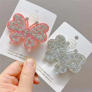 Macro shot of two handmade butterfly hair clips with sparkling rhinestones on paper card