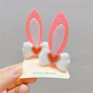 Pair of pink glitter bunny ear hair clips with white plush bows and red sequin hearts