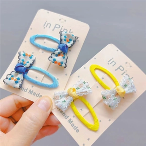 Detailed close-up of blue floral and yellow lace handmade fabric bow hair clips for kids