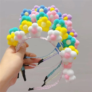 Détail d'un serre-tête fleuri en peluche colorée avec pompons et structure antidérapante