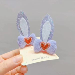 Detail showing plush rabbit ear hair clips with red rhinestone hearts and glitter texture