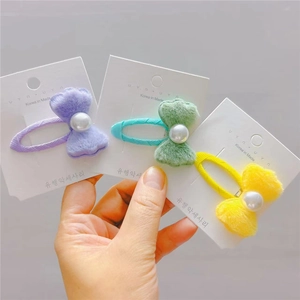 Détail de trois barrettes à nœuds en peluche avec perles en violet, vert et jaune