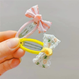 Close-up of pink plaid and floral lace fabric bow hair clips for girls held in hand