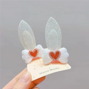 Detailed view of plush white rabbit ear hair clips with red rhinestone heart center decorations