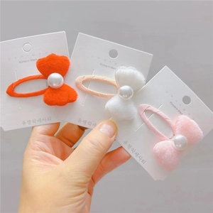 Détail de barrettes à nœuds en peluche avec perles en orange, blanc et rose