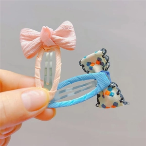 Detail showing pink textured fabric and floral print bow hair clips with metal BB bases