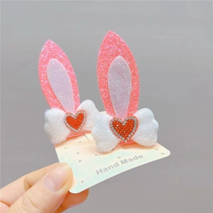 Detail of pink sequin rabbit ear hair clips with white plush bows and red heart rhinestones