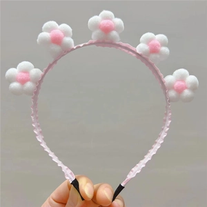 Détail du serre-tête fleurs en peluche rose avec boules macaron sur bande ondulée