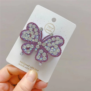 Detail of purple butterfly hair clip with hand-made rhinestones on white card