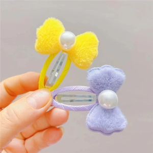 Détail des barrettes à cheveux en peluche jaune et violette avec perles blanches