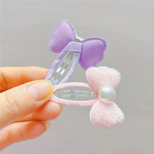 Détail de barrettes à cheveux avec nœud en ruban violet et nœud en peluche rose