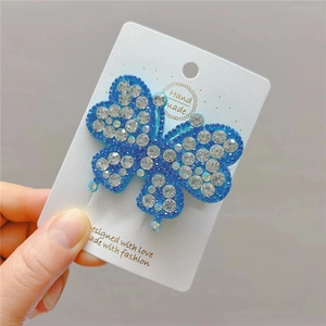 Detailed macro view of an elegant blue rhinestone butterfly hair clip on a gift card