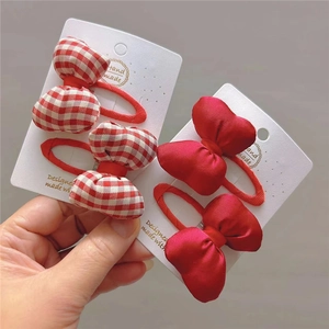 Hand holding red plaid and satin bow hair clips on display cards in detail