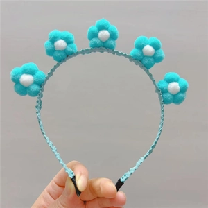 Détail de cinq ornements de tournesol en peluche macaron sur un serre-tête en tissu bleu