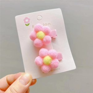Handheld display of cute pink and yellow plush flower hair clips for young girls