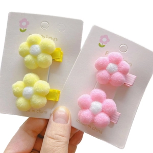 Plush flower hair clips in pink and yellow with soft fur balls for kids hair styling