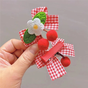 Detail of red and white plaid bow hair clip with handmade crochet flower and cherries
