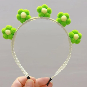 Détail de serre-tête fleurs en peluche avec pompons vert et blanc décoratifs