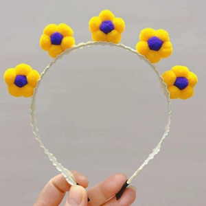 Vue détaillée du serre-tête tournesol avec pompons colorés et texture douce en peluche