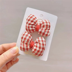 Detail of red and white gingham bow hair clips with handmade gold lettering on card