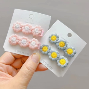Detailed view of hand-held crochet flower hair clips with soft pink and blue embroidered petals