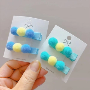 Close-up of colorful polyester pom-pom hair clips on a white display card package