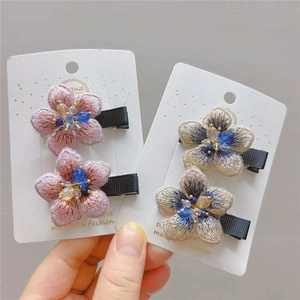 Detailed embroidery on floral hair clips with crystal bead centers and metal base