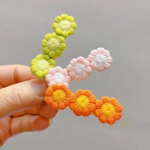 Close-up of three handmade crochet flower hair clips in green, pink, and orange colors