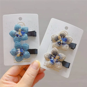 Close-up of premium embroidered flower hair clips with hand-sewn beads on card