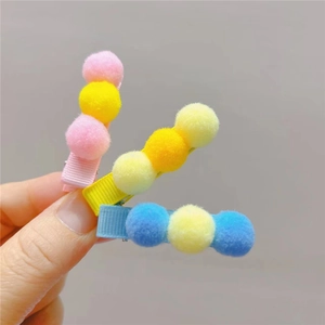 Close-up of candy-colored plush ball hair clips set with ribbed ribbon crocodile clips