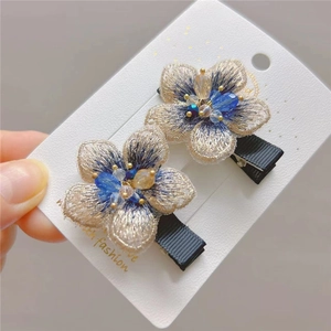 Close-up of premium embroidered floral hair clips with crystal bead centers and rich texture