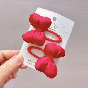 Close-up of two handmade red satin bow hair clips on a white display card for girls