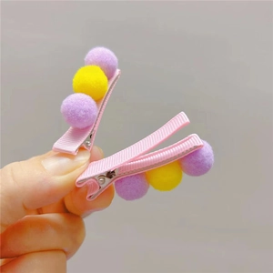 Detail of cute kids' duckbill clips featuring colorful plush balls and pink ribbon wrap