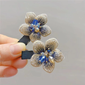 Detailed close-up of embroidered flower hair clips with blue crystals and beads