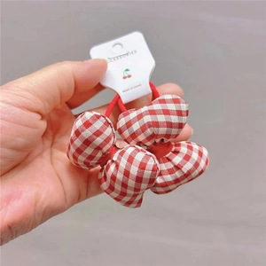 Close-up of red and white gingham bow hair tie on a white accessory display card