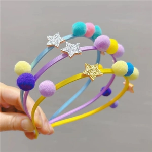 Gros plan de serre-têtes pour enfants avec pompons colorés et étoiles à paillettes en main