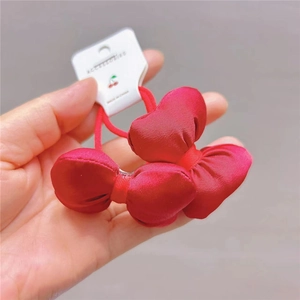 Macro shot of red satin bow hair ties with cherry tags for girls and women
