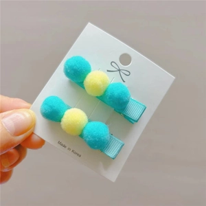 Detailed view of handmade plush ball hair clips in green and yellow for girls
