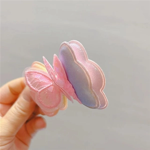 Détail d'une pince à cheveux papillon rose et violet avec broderie et paillettes
