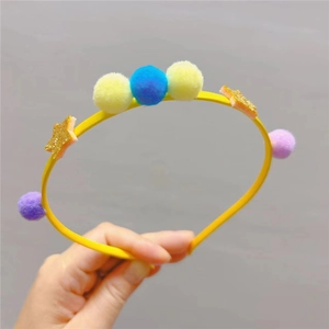 Détail d'un serre-tête jaune pour enfant avec pompons colorés et étoiles dorées