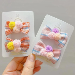Dettaglio di fermagli per capelli a quadretti con morbidi pompon colorati