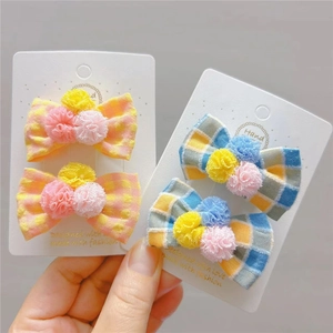 Dettaglio delle mollette per capelli a quadretti fatte a mano con pompon colorati