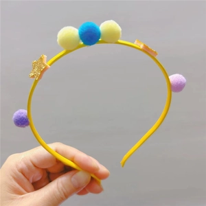 Détail d'un serre-tête jaune avec pompons multicolores et ornements d'étoiles brillants