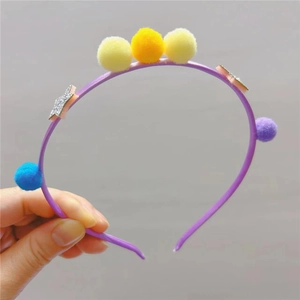 Gros plan d'un serre-tête violet pour enfants avec pompons colorés et étoiles pailletées