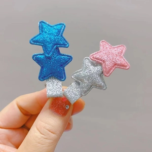 Detail of glittery star hair clips for children with shiny fabric finish and metal base
