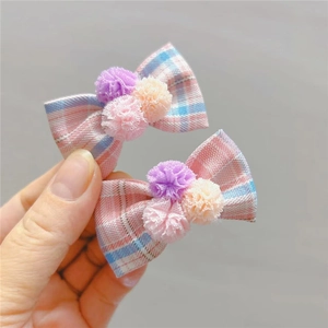 Dettaglio di fermagli per capelli a quadretti rosa e blu con morbidi pompon per bimbe