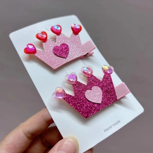 Close-up of glitter crown hair clips with heart gemstones for girls in pink colors