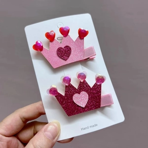 Detail of pink heart-shaped crown hair clips with sparkling glitter and jewels